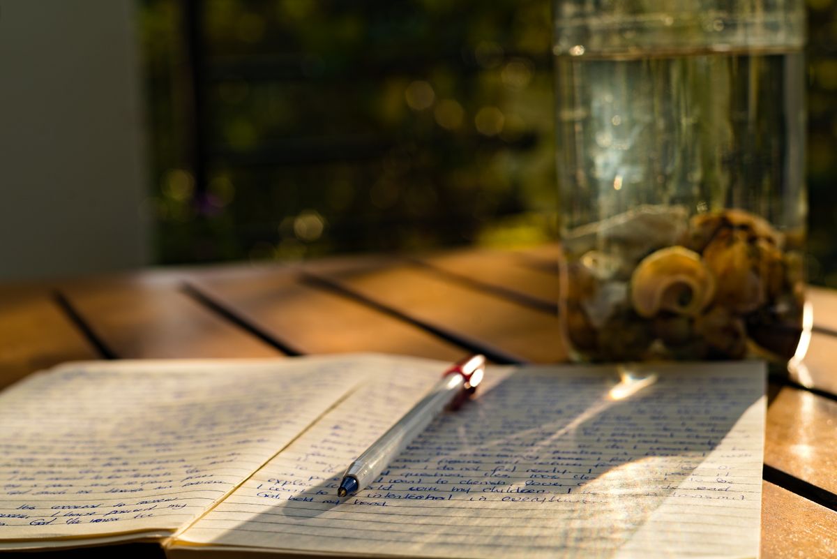 A notebook and pen on a sunlit table, perfect for reflection and writing in Kampala, Uganda.